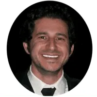 A man smiling, dressed in a black suit and tie, embodies professionalism against a dark backdrop. The image, reminiscent of an accomplished IT services expert, is elegantly framed in a black oval.